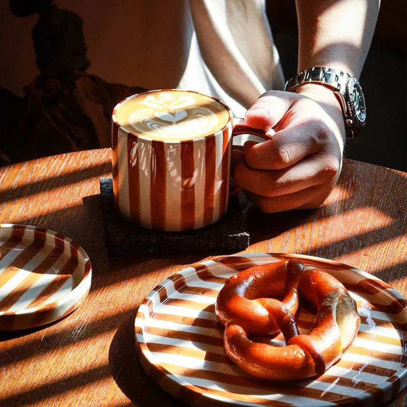 Handgezeichnetes Set aus gestreifter Keramiktasse und Untertasse